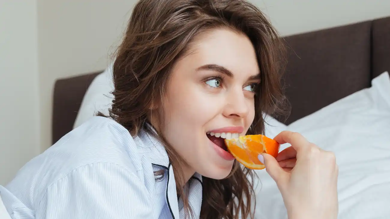 Mujer comiendo naranja para aliviar el resfriado